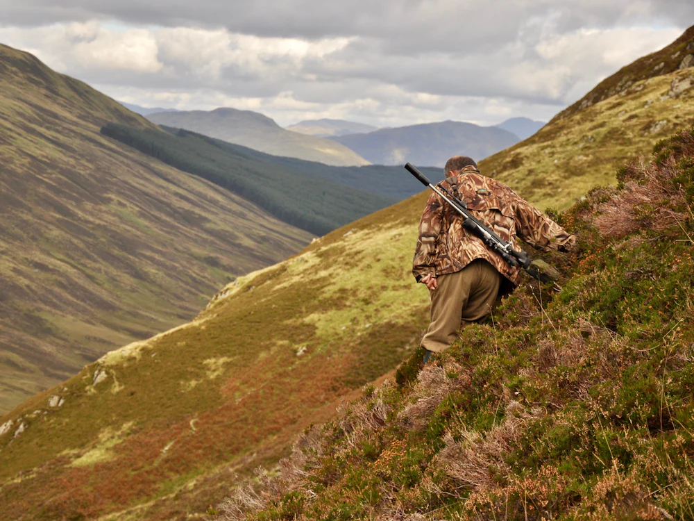 Cazador subiendo al monte con el rifle al hombro