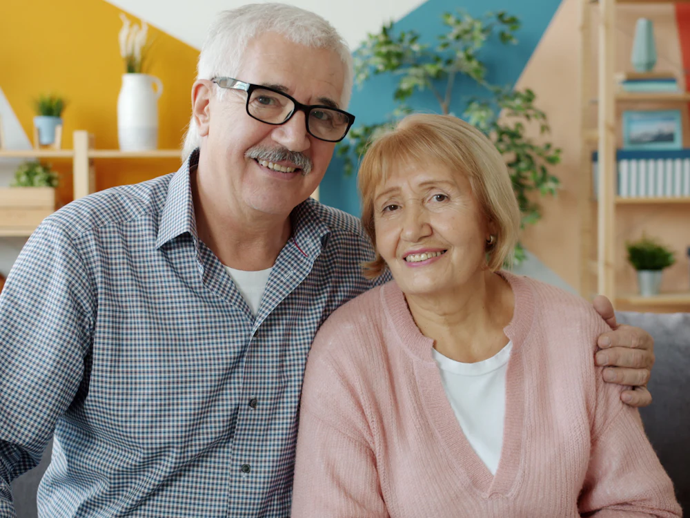 Pareja de mayores sonriendo en el salón